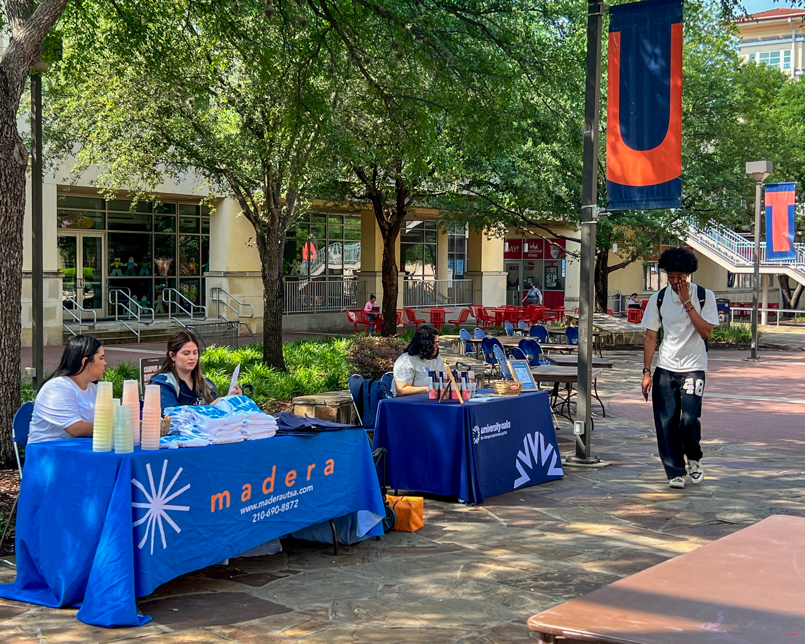 Two organizations tabling with a student walking by