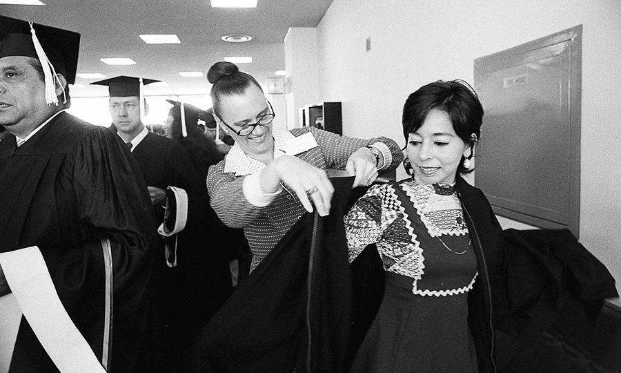 Rebecca Underwood of the university admissions office helps Graciela Guerra with her robe prior to the ceremonies.