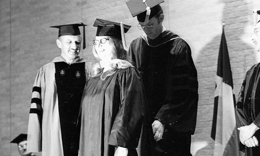 Edward “Doug” Hodo, dean of the College of Business, hoods UTSA’s first graduate, Susan Bolado.