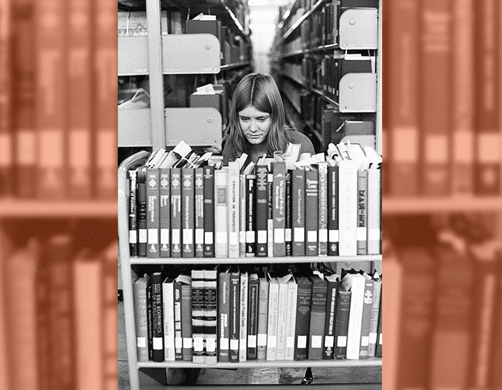 Terry Meier sorts a set of books on a cart for shelving in the library.