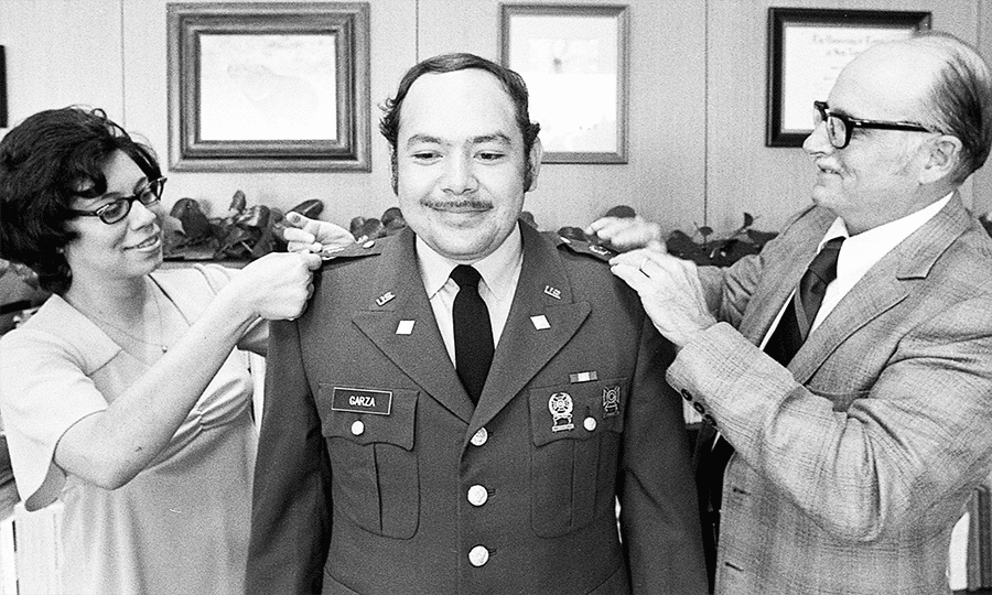 Raymond Garza receives his second lieutenant bars from his wife and President Flawn.