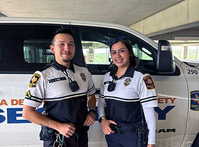 Male and female UTSA PD officer standing in front of a police vehicle inside a parking garage