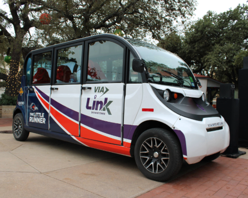 A small 6-passenger electronic vehicle called "the Little Runner", white with blue, orange and purple markings and a roadrunner head with the words "The little Runner and the back side panel and Via Link written on the door.