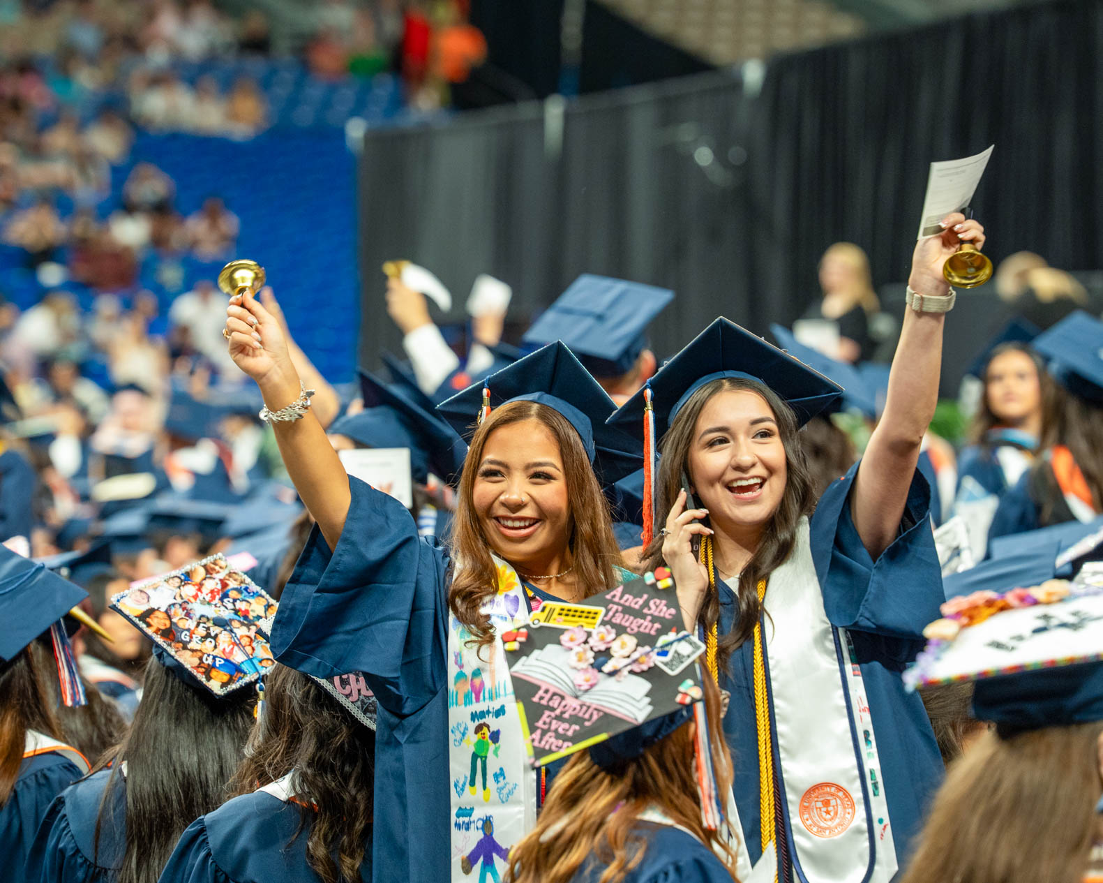 two girls in cap and gown celebrating graduation