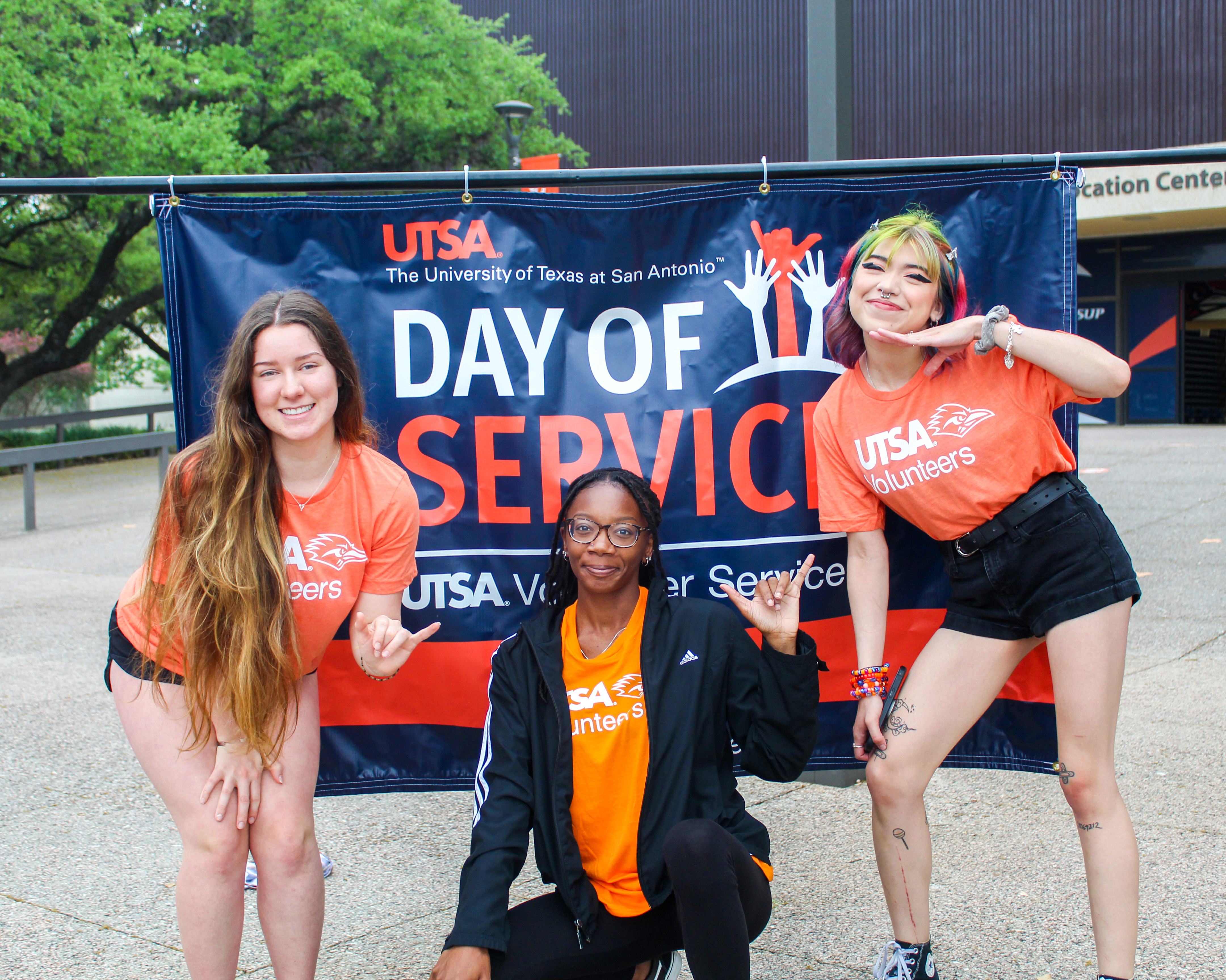 Three students in front of a sign that says Day of Service