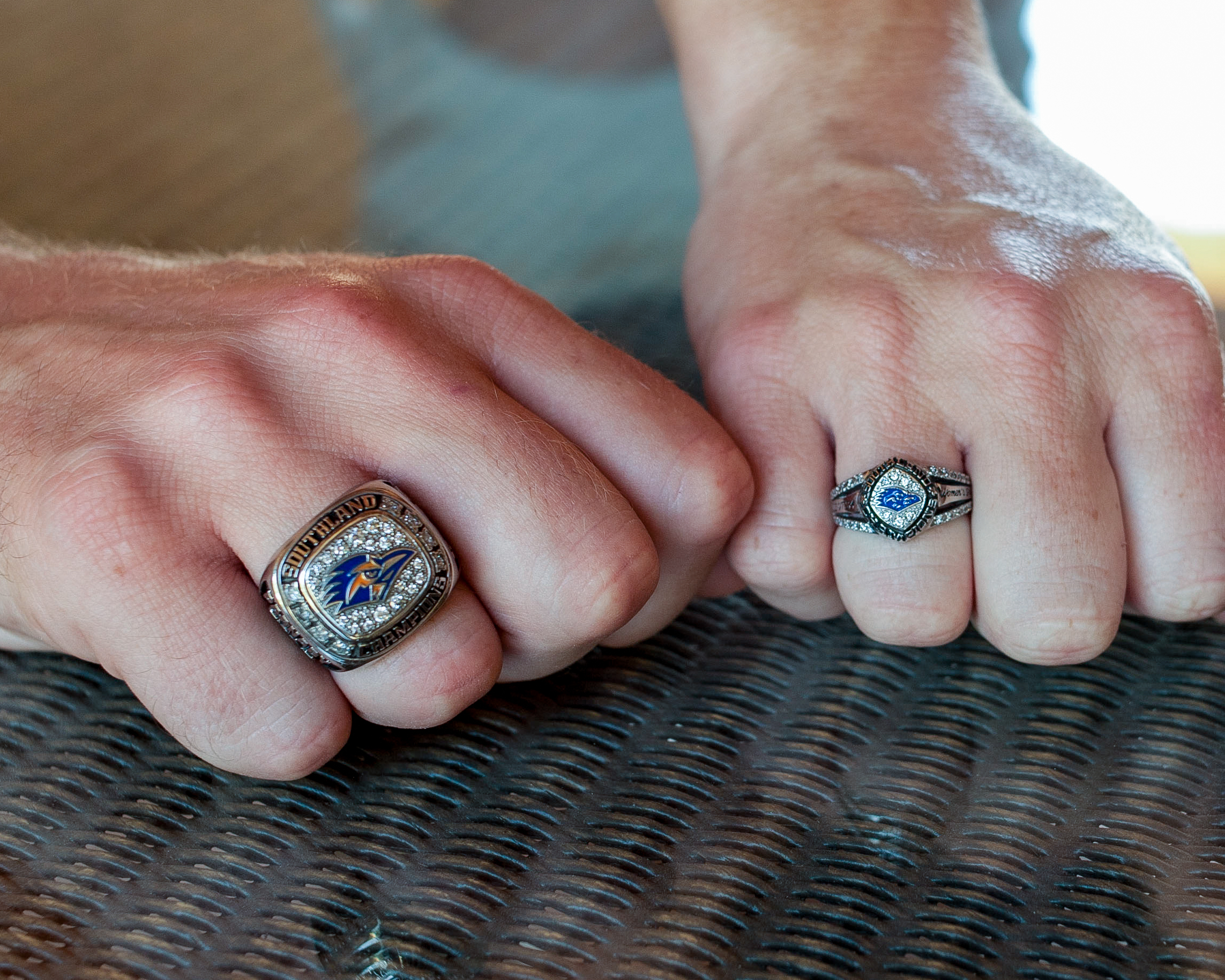 Two hands with one UTSA graduation ring on each hand, on the left the Male graduation ring and on the right the female graduation ring