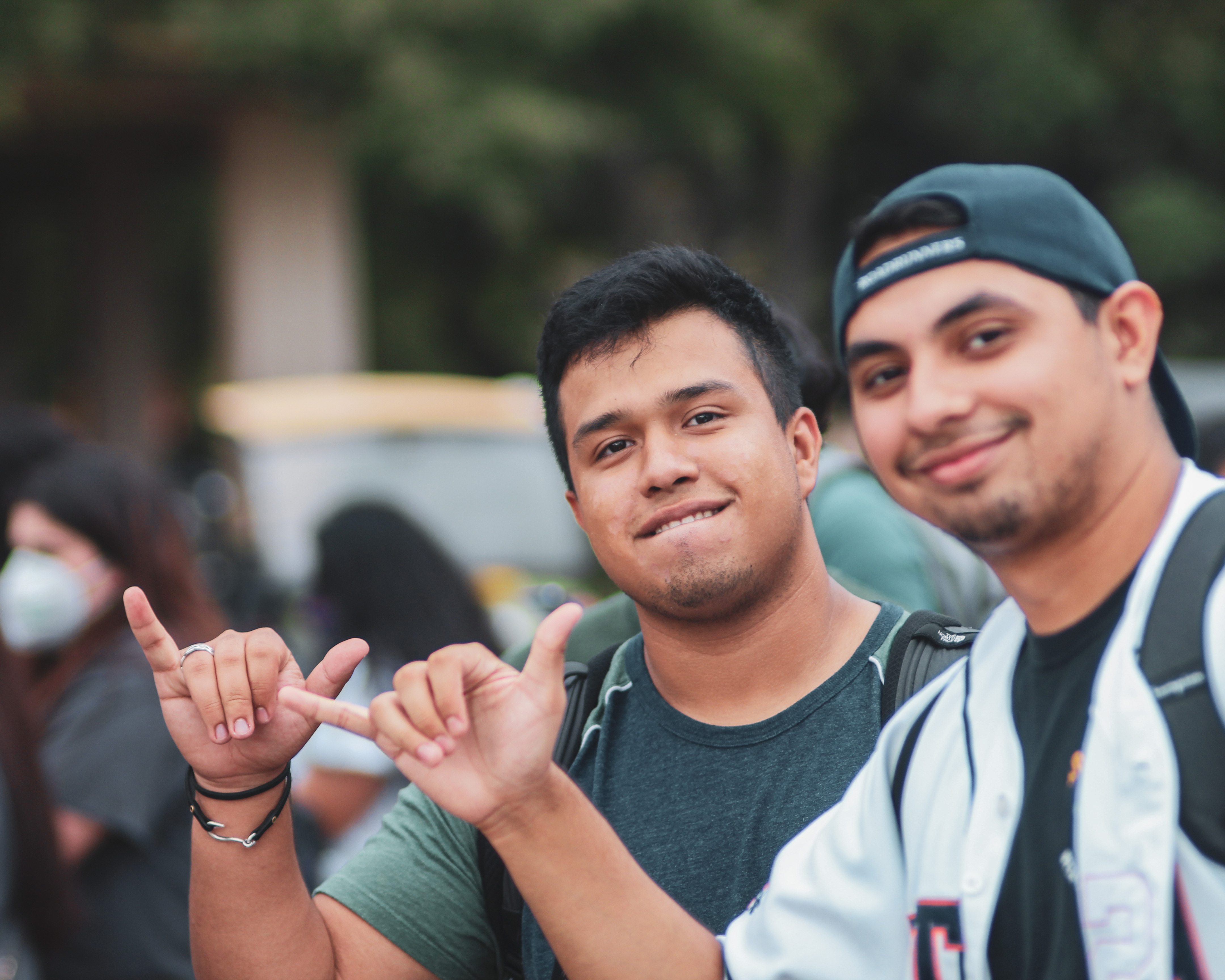 Two students smiling holding up the "Birds Up" hand sign.