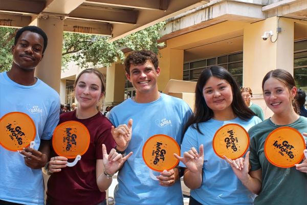 Five students holding orange fans at Get Involved Fair