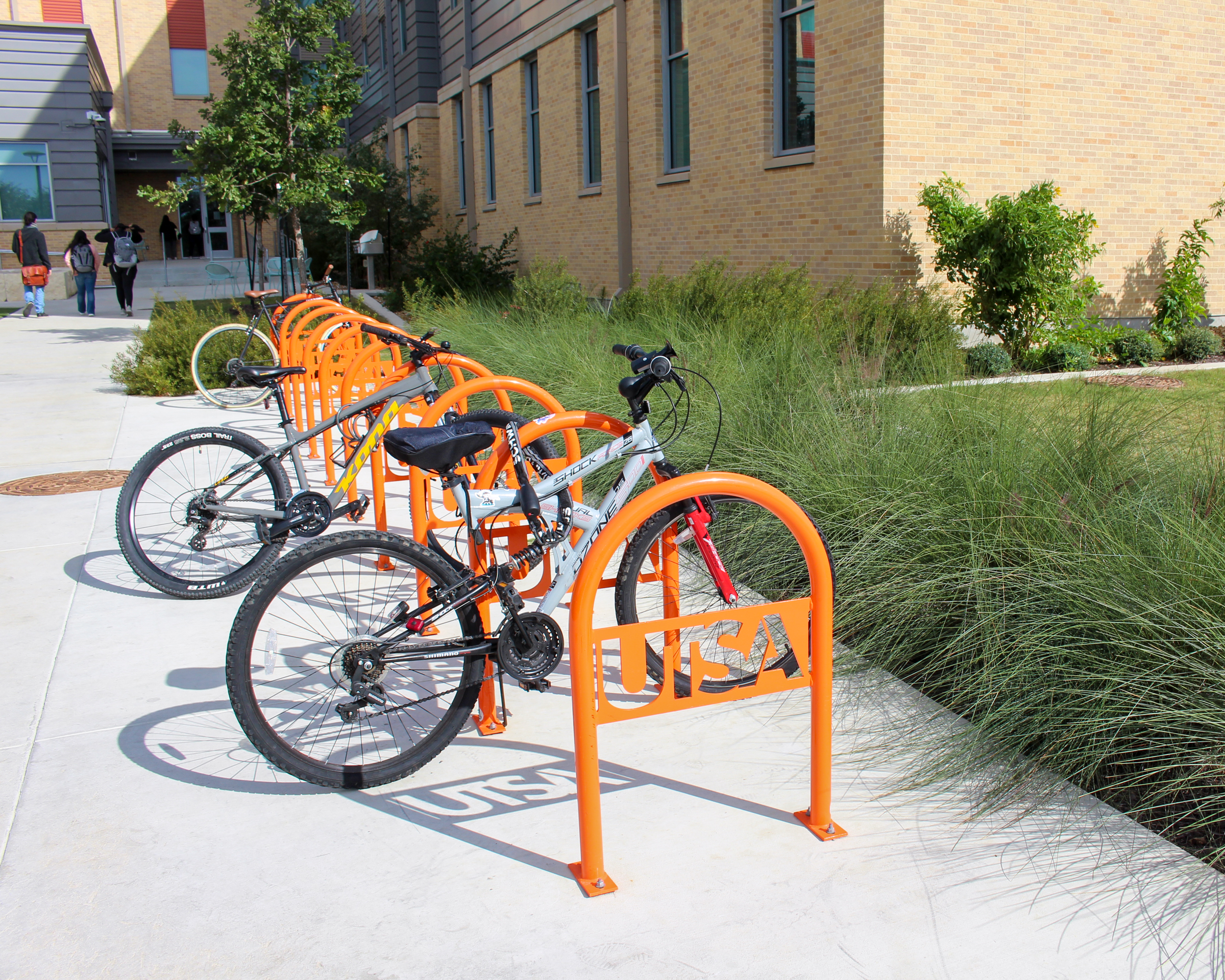 Two bikes locked at a orange UTSA bike rack