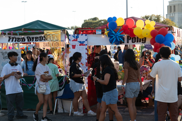 students standing in front of two carnival booths decorated with balloons
