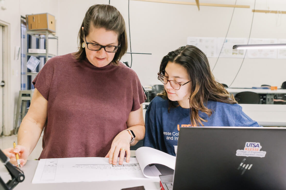 Instructor with student looking at a book