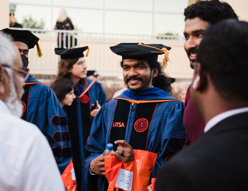Student in a doctoral hood smiling at his parent
