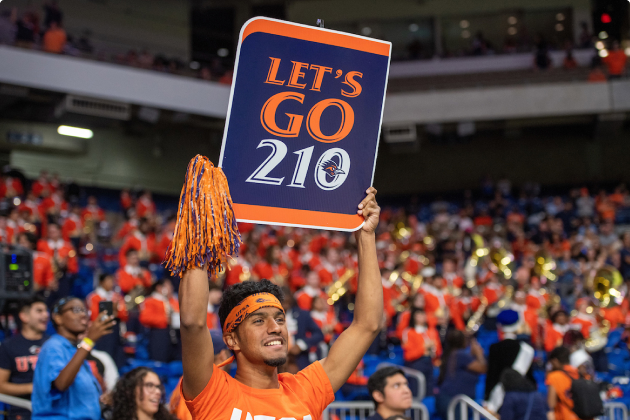 Student holding a 'Let's Go 210' sign at a UTSA Football game