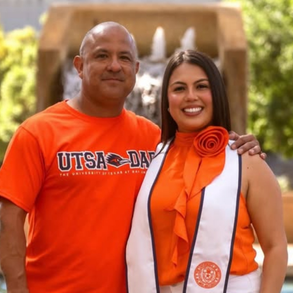 Two people standing in front of the sombrilla fountain smiling