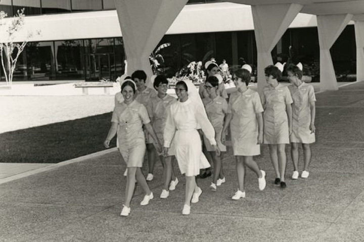 A black and white photo of past student nurses walking through campus