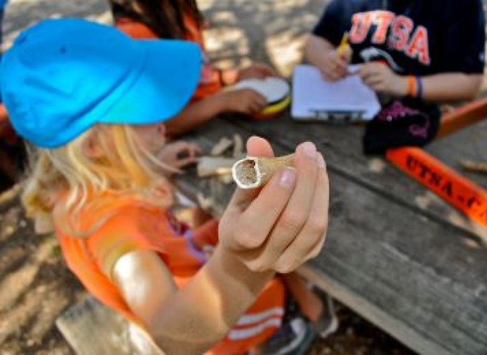A girl holding up a old bone fossil
