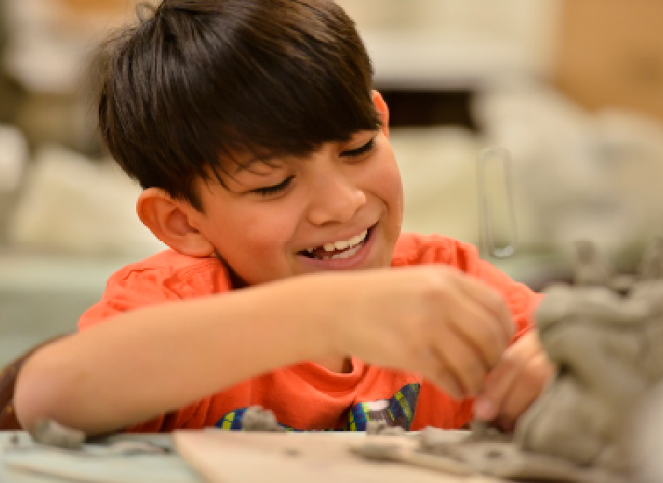 A young boy making a art project with modeling clay