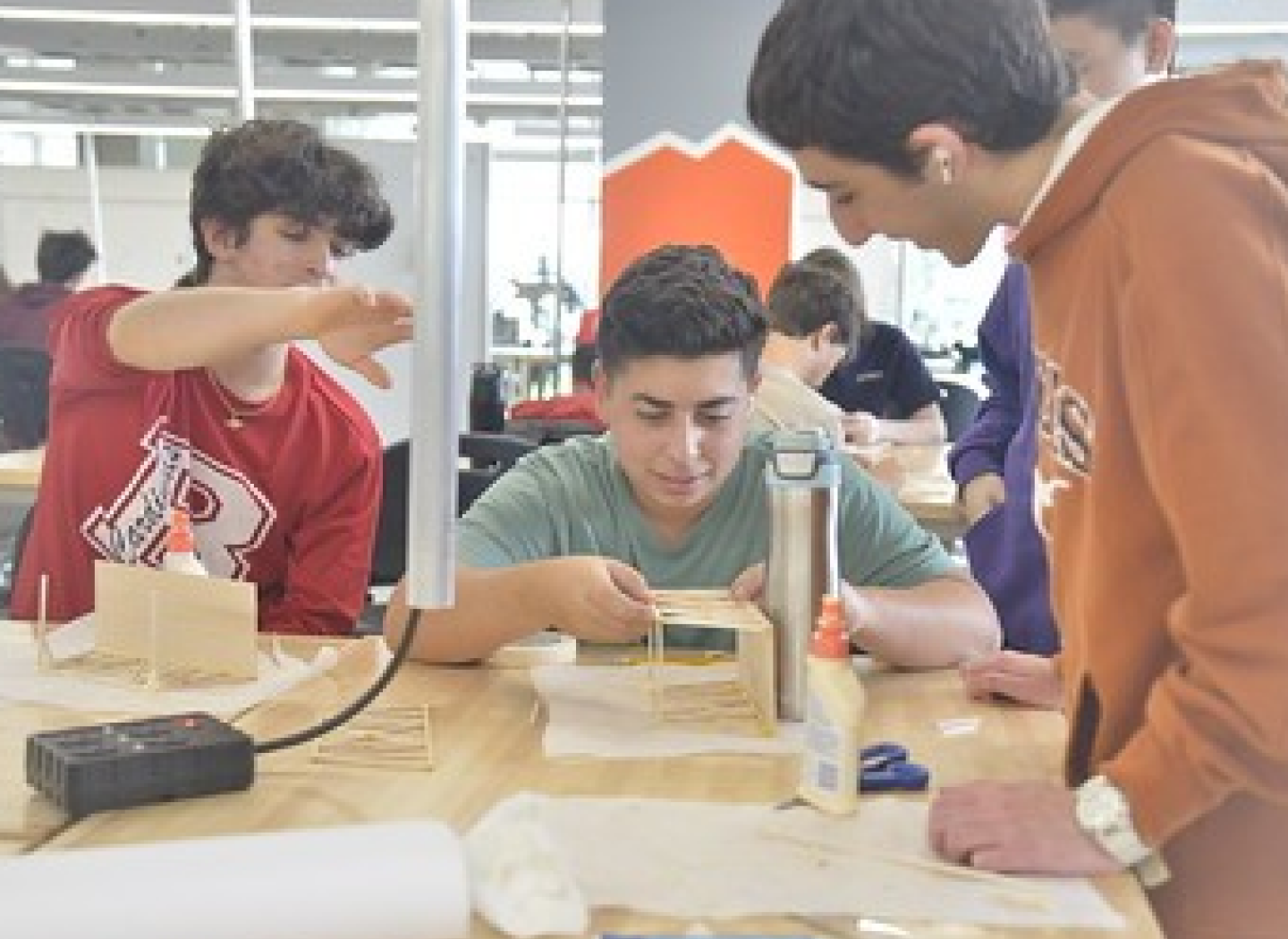 Three male students constructing a structure on a table