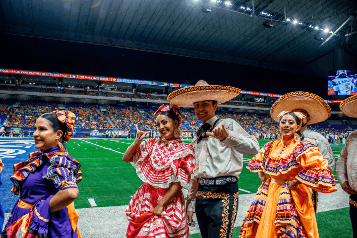 Student dress in Mariachi and folkorico dresses on a football field