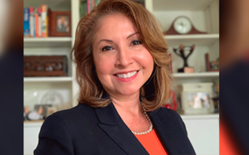 Teresa Niño smiling in a black blazer and orange top