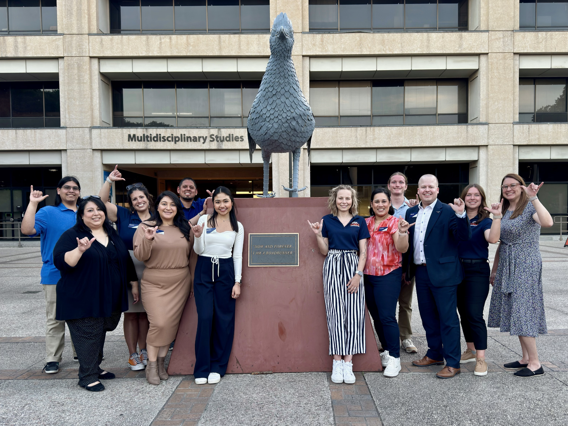 UTSA Alumni Staff giving birds up at roadrunner statue