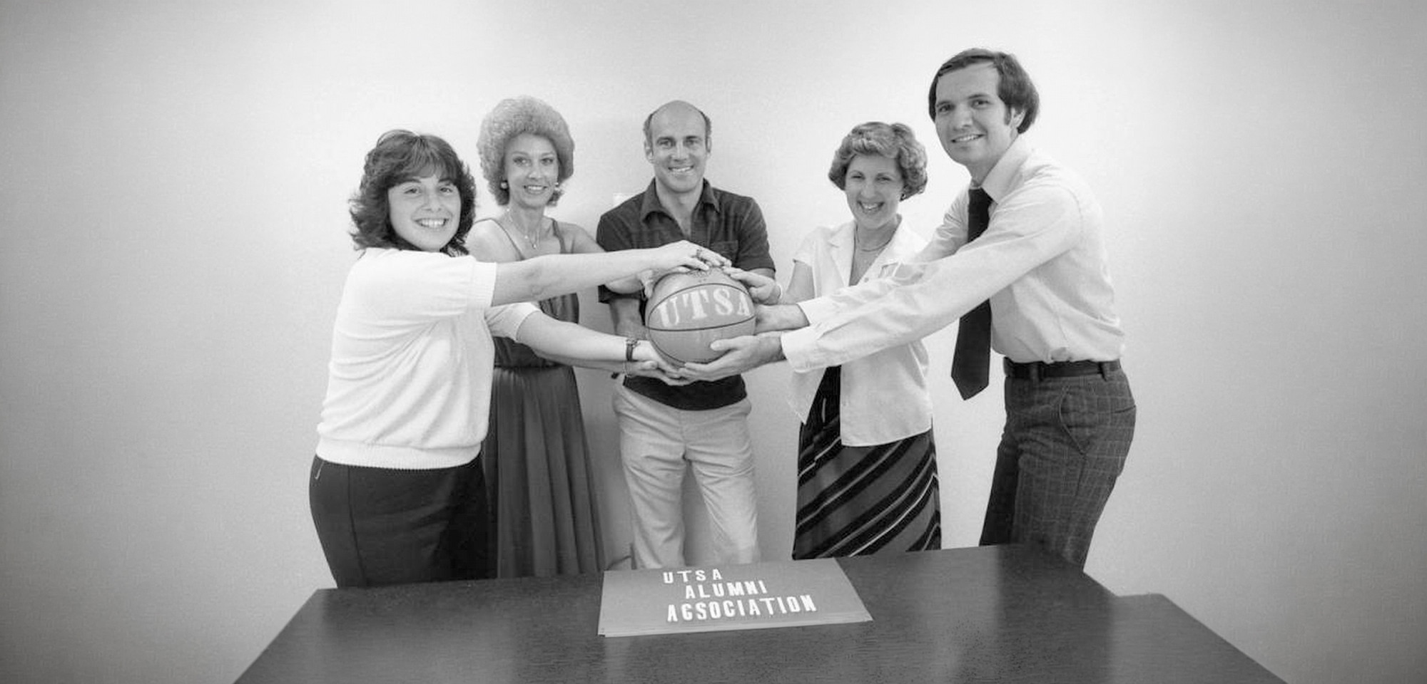 UTSA Alumni Association Members touching a basketball