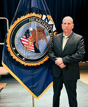 Capt. Thomas Calucci standing by FBI flag