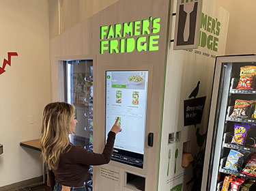 Picture of girl using Farmers Fridge vending machine.