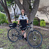 Officer Lewis posing behind her bike outside near a tree