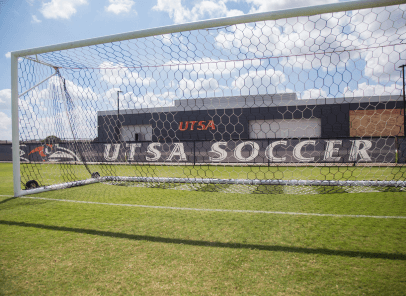 Soccer goal post with a banner in the background that reads 'UTSA Soccer'.