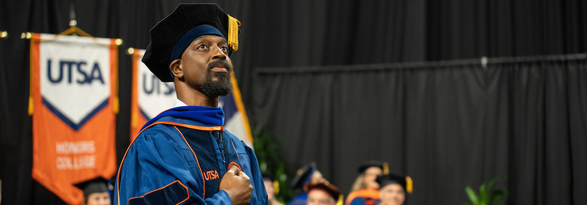 Doctoral degree recipient in full regalia looking proud during commencement