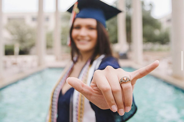 Graduate in full regalia showing off her UTSA ring