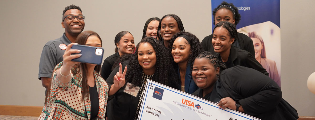 Students taking a photo with the check they won