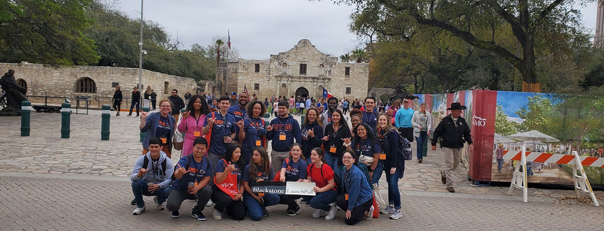 Group of students in front of the Alamo with a sign that says Blackstone Launchpad