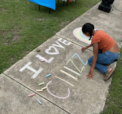 student writing on sidewalk with chalk