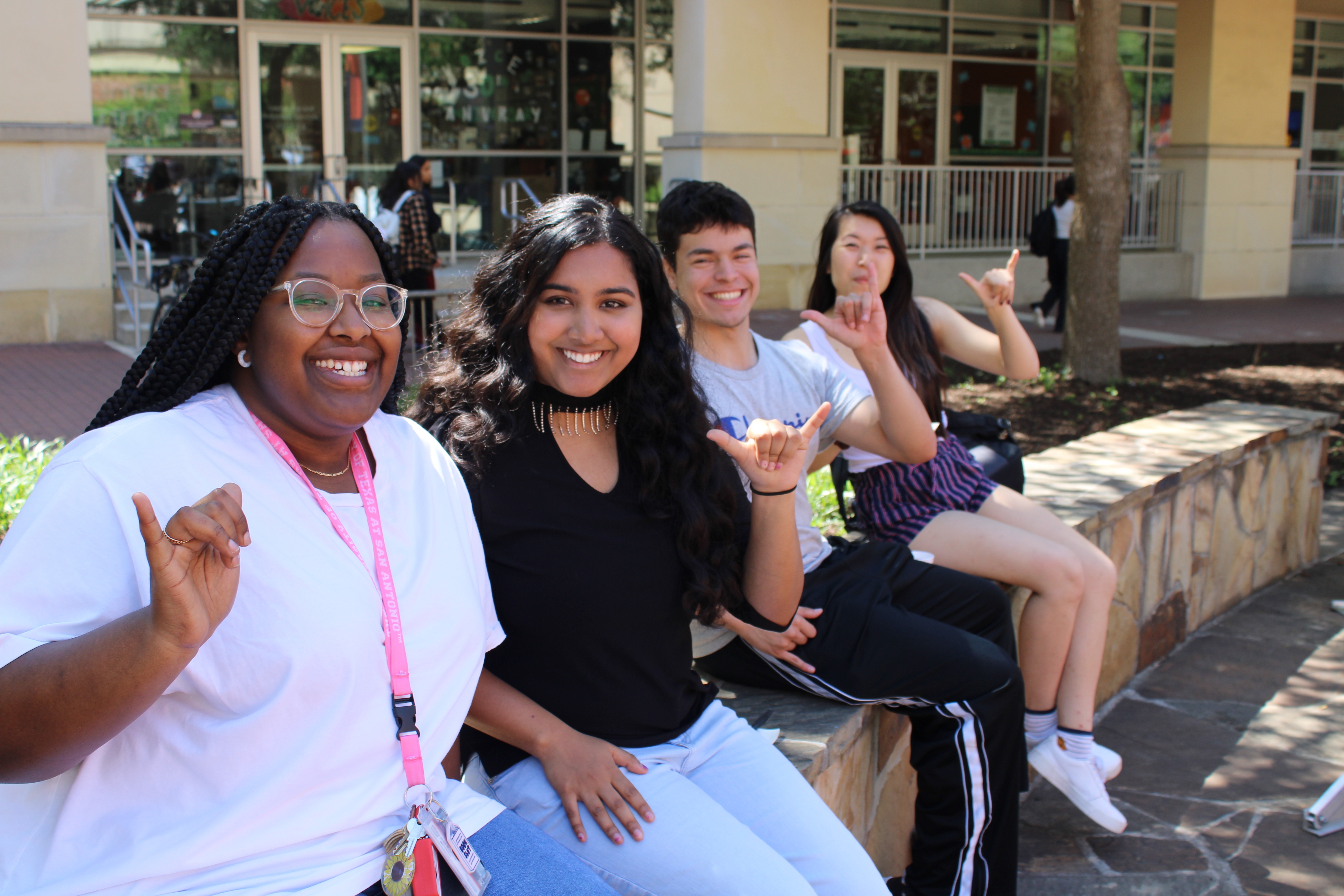 four students sitting along the SU paseo