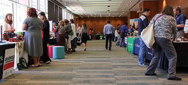 Vendor Fair event - people standing next to vendor fair tables interacting with vendor fair representatives.