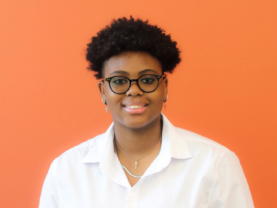 Alanah Penn smiling in front of orange background