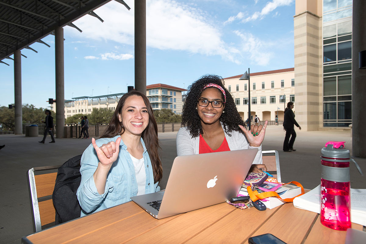 Two students giving birds up on campus