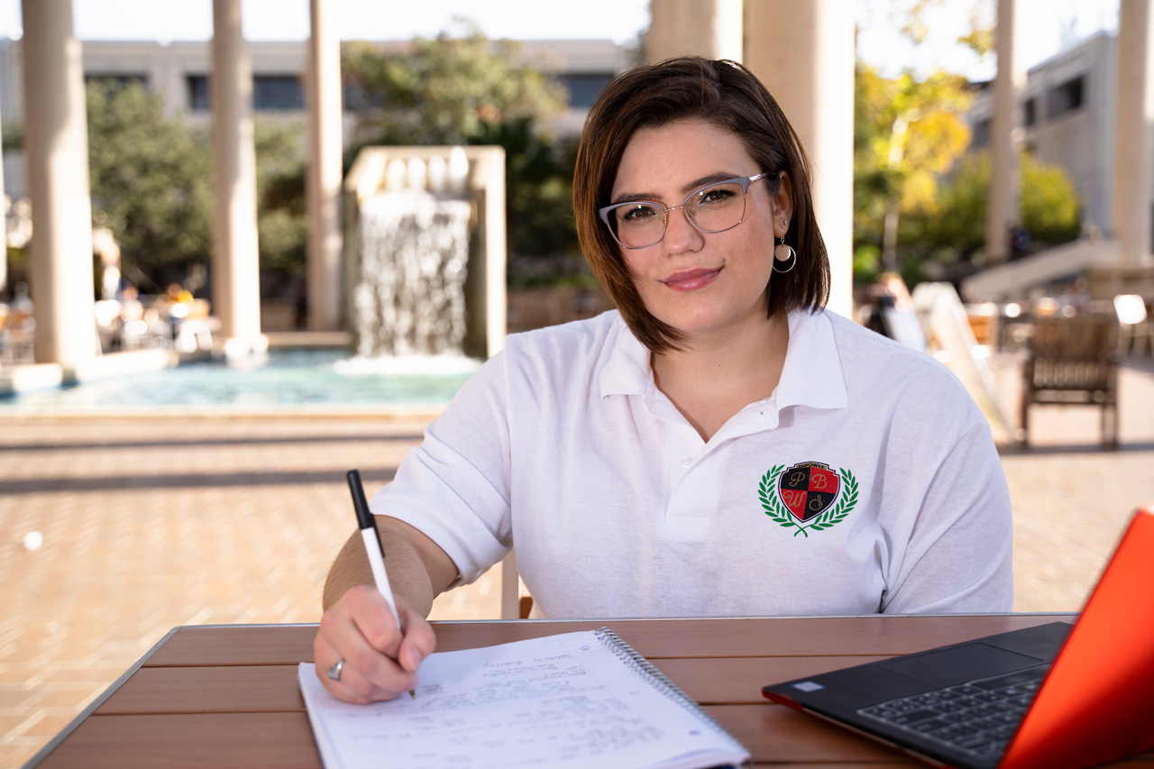 a female student working on an assignment outdoor with a laptop