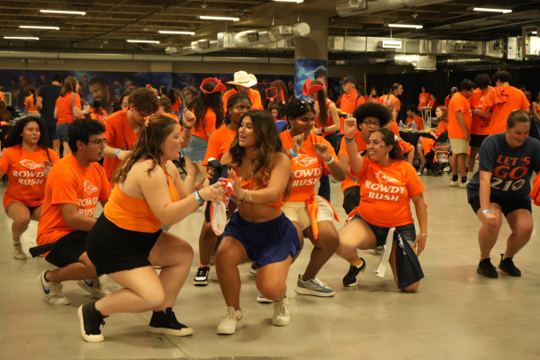 group of students line dancing wih people in the background sitting at tables