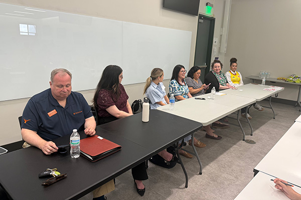 A group of people at a table at the front of the class talking to others