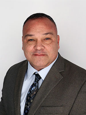 headshot of Marco Garcia wearing a brown business suit.