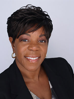 Phranses Williams portait - short brown hair, smiling and wearing business suit