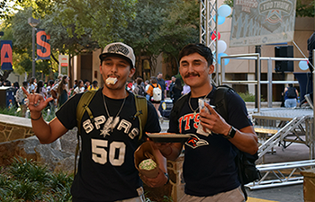 Two male students laugh while eating paletas at the National Night Out event.
