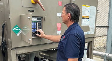 Facilities Service Male employee looking at and touching a control keypad