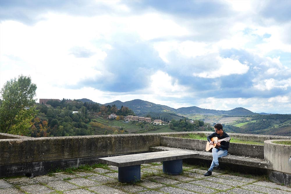 Taking advantage of the beautiful Tuscan landscape, UTSA engineering student Alberto Ruiz plays a guitar at the University of Urbino in Urbino, Italy.