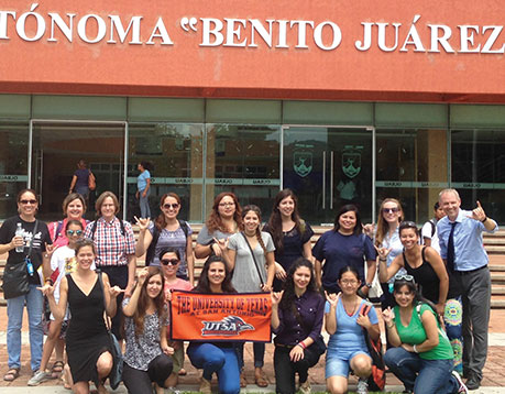 A Study Abroad group from the Department of Bicultural-Bilingual Studies, led by Drs. Peter Sayer and Patricia Sánchez, poses in front of their host university, Universidad Autónoma Benito Juárez de Oaxaca.