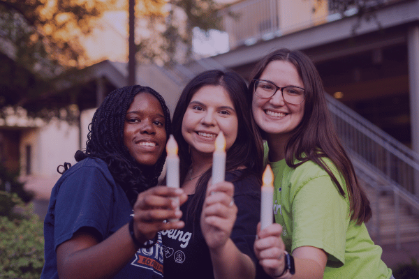 three female students holding candle lights