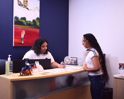 student employee speaking to a visitor at the Student Assistance Services front desk 